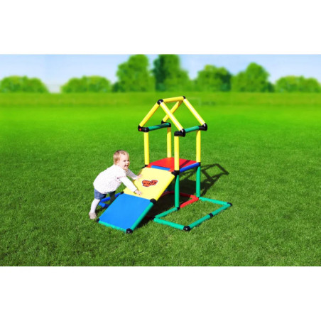 Ein Kleinkind spielt auf einem bunten Klettergerüst mit Rampen auf einer Wiese unter blauem Himmel.