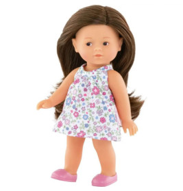 Puppe mit langen braunen Haaren, Blumenkleid und rosa Schuhen steht vor weißem Hintergrund.