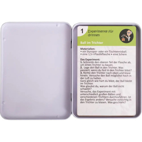 Offene Dose mit einer Karte darin, die eine Anleitung für ein naturwissenschaftliches Experiment auf Deutsch zeigt.