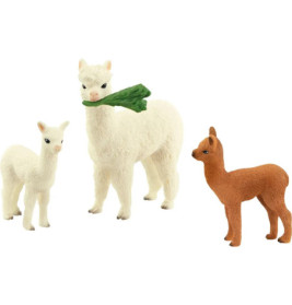 Drei Alpaka-Spielzeuge, zwei weiße und ein braunes eines der weißen hält ein grünes Blatt im Maul.
