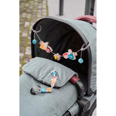 Grauer Kinderwagen mit bunten Spielzeugen am Lenker und einem weiteren Spielzeug vorne befestigt.