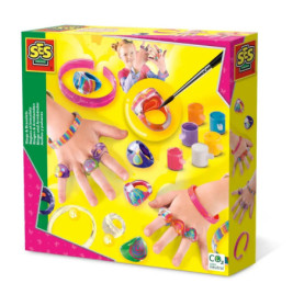 Bastelset mit bunten Ringen, Armbändern, Farbtöpfen und Pinsel auf Gelb, Hände zeigen Schmuck.