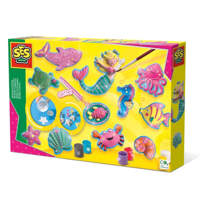 Bunte Bastelbox mit Meerjungfrauen-Motiv, Meerestieren, Farben und Glitzer auf gelbem Hintergrund.