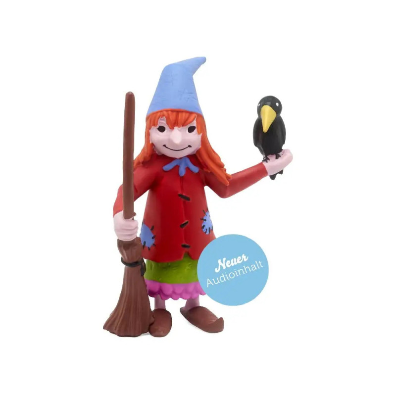 Tonfigur einer Hexe mit Besen, blauem Hut, rotem Mantel und einem schwarzen Vogel auf ihrer Hand.