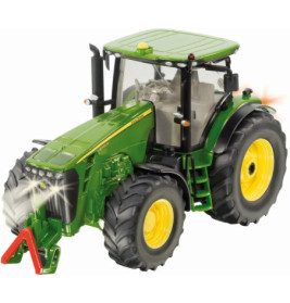 Grüner und gelber Spielzeugtraktor mit eingeschaltetem Licht und großen schwarzen Reifen aus Front-Links-Perspektive.