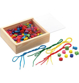 Holzbox mit bunten Fädelperlen und Schnüren, einige Perlen und Schnüre liegen daneben auf der Fläche.