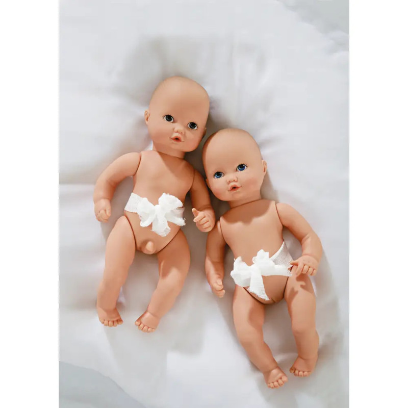Zwei Babypuppen mit weißen Schleifen an der Taille liegen nebeneinander auf einer weißen Decke.