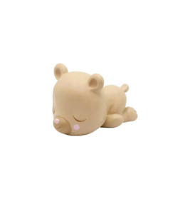 Beigefarbene Bärenfigur schläft auf dem Bauch, hat geschlossene Augen und rosafarbene Wangen.