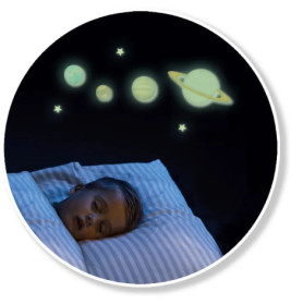 Ein Kind schläft im Bett, über ihm leuchten nachtleuchtende Planeten und Sterne an der Wand.
