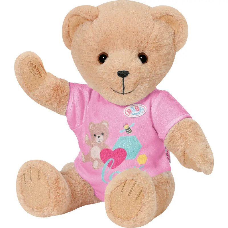 Ein hellbrauner Teddybär im rosa Shirt mit Bären- und Herzmotiv sitzt und winkt.