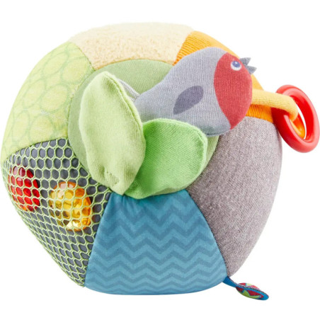 Bunter, weicher Stoffball mit kleinem Vogel, verschiedenen Strukturen und rotem Kunststoffring. Bunter, weicher Stoffball mit kleinem Vogel, verschiedenen Strukturen und rotem Kunststoffring.