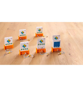 Sechs Lernspielkarten in orangefarbenen Haltern mit angeschlossenen Ohrhörern auf hellem Holzfußboden.