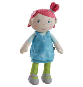 Plüschpuppe mit roten Haaren, blauen Augen, blauem Kleid, grüner Leggings und grauen Schuhen lächelt.
