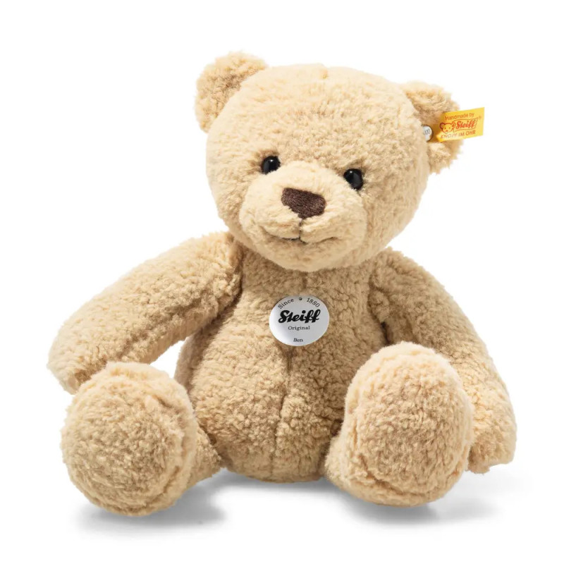 Ein hellbrauner Steiff-Teddybär sitzt aufrecht vor weißem Hintergrund, das Markenetikett auf der Brust.