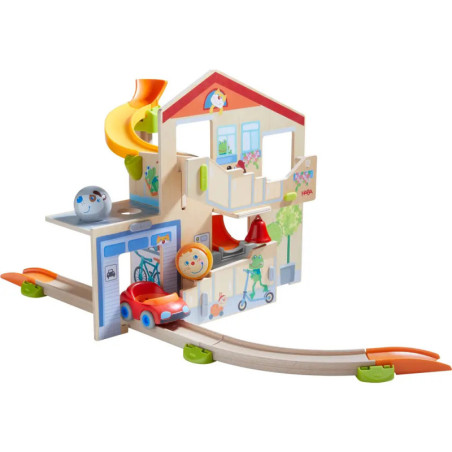 Holzspielhaus mit Rutsche, Schienen, rotem Spielzeugauto und kindgerecht dekorierten Wänden.