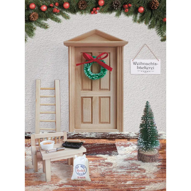 Miniaturszene: Weihnachtstür mit Kranz, Schild, Baum, Leiter, Stuhl und Backutensilien auf verschneitem Teppich.