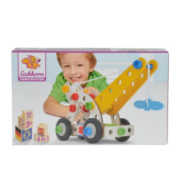Lächelndes Kind spielt mit Eichhorn Constructor Kran-Set, Karton zeigt 65 Teile und Altersempfehlung ab 3 Jahren.