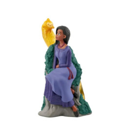 Eine Figurine einer Frau im lila Kleid sitzt neben einem gelben Vogel auf einem grünen Baumstamm.