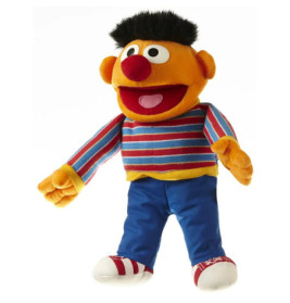 Ein Plüschtier mit oranger Haut, schwarzen Haaren, gestreiftem Shirt, blauer Hose und Sneakern lächelt breit.