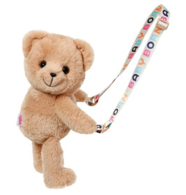 Ein brauner Plüsch-Teddybär hält ein buntes Band mit der Aufschrift BABY BORN in farbigen Buchstaben.