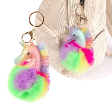 Zwei Einhorn-Schlüsselanhänger mit Regenbogenmähnen und bunten Pompons hängen an einer beigefarbenen Tasche.