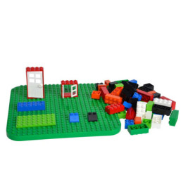 Grüne Grundplatte mit montierten Türen und daneben verstreuten, bunten Bausteinen.