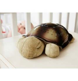 Ein Plüsch-Schildkröten-Nachtlicht steht auf einem Tisch neben einem Babybett mit einem Baby darin.