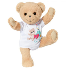 Hellbrauner Teddy mit weißem Shirt und bunten Motiven, steht auf einem Bein und hebt beide Arme.