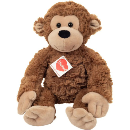 Plüschaffe in Braun mit beigem Gesicht, Ohren, Händen und Füßen, sitzt aufrecht und trägt ein herzförmiges Etikett.