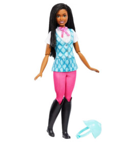 Eine schwarze Barbie in Reitkleidung mit pinker Hose, schwarzen Stiefeln und blauem Helm auf dem Boden.