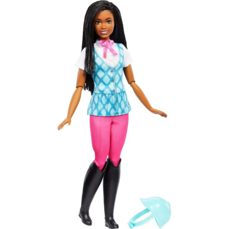 Eine schwarze Barbie in Reitkleidung mit pinker Hose, schwarzen Stiefeln und blauem Helm auf dem Boden.