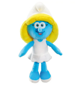 Plüschfigur eines blauen Cartoon-Charakters mit gelben Haaren, weißem Hut, Kleid und Schuhen, lächelnd.