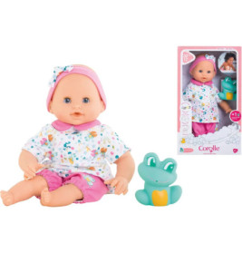 Babypuppe im bunten Outfit mit Spielzeugfrosch neben der Verpackung, die Puppe und Zubehör zeigt.