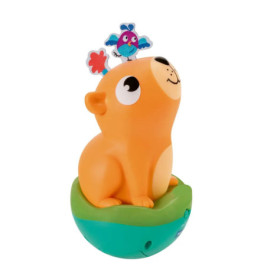 Oranges Capybara-Spielzeug sitzt auf grünem Sockel, ein kleiner blauer Vogel steht auf seinem Kopf.