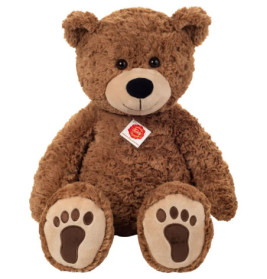 Großer, flauschiger brauner Teddybär mit einem Anhänger um den Hals sitzt aufrecht und schaut nach vorne.