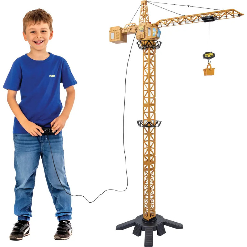 Ein Junge im blauen Hemd steuert mit einer Fernbedienung einen großen Spielzeug-Baukran.