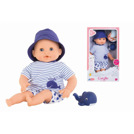 Babypuppe im gestreiften Outfit und blauer Mütze mit Spielzeugwal neben ihrer Verpackung gezeigt. Babypuppe im gestreiften Outfit und blauer Mütze mit Spielzeugwal neben ihrer Verpackung gezeigt.