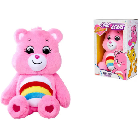 Ein rosa Care Bear Plüsch mit Regenbogen auf dem Bauch sitzt neben seiner bunten Verpackungsschachtel.