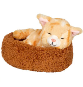 Ein orangefarbenes Kuscheltier in Katzenform schläft in einem runden, braunen, flauschigen Tierbett.