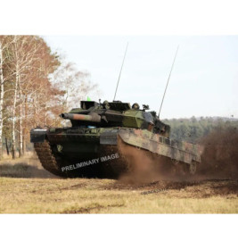 Ein Panzer fährt schnell über Gras und wirbelt Erde auf, mit Bäumen und Himmel im Hintergrund.