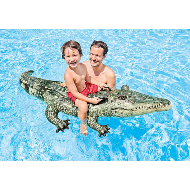 Ein Mann und ein Kind lächeln auf einem Krokodil-Pool-Float im klaren, blauen Wasser.