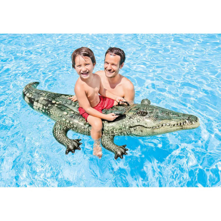 Ein Mann und ein Kind lächeln auf einem Krokodil-Pool-Float im klaren, blauen Wasser.