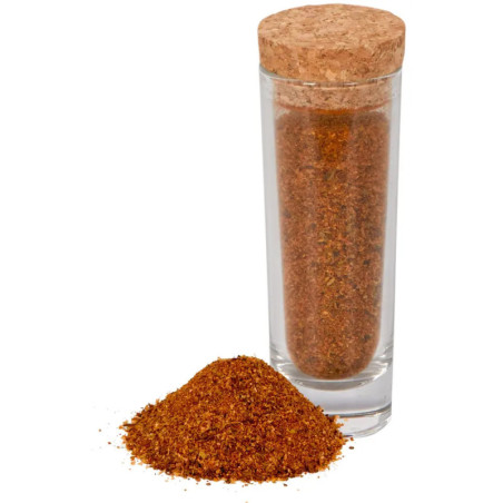 Ein Glasgefäß mit Korkdeckel, gefüllt mit Gewürzmischung, daneben etwas lose Gewürze.