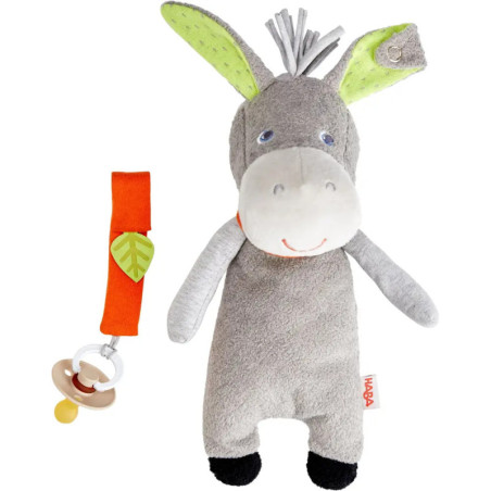 Graues Esel-Plüschtier mit grünen Ohren neben orangem Schnullerband und beigem Schnuller.