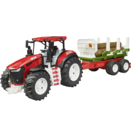Roter Spielzeugtraktor mit großen Rädern zieht grüne Anhänger mit Holzstämmen an.