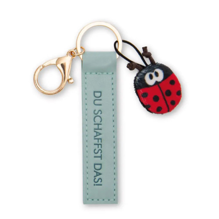 Schlüsselanhänger mit grünem DU SCHAFFST DAS!-Schild und kleinem Marienkäfer-Anhänger.