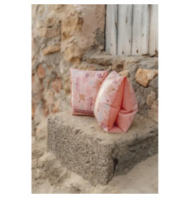 Zwei pinke Schwimmflügel mit Strandmotiv liegen auf einer Steinstufe an einer verwitterten Wand.