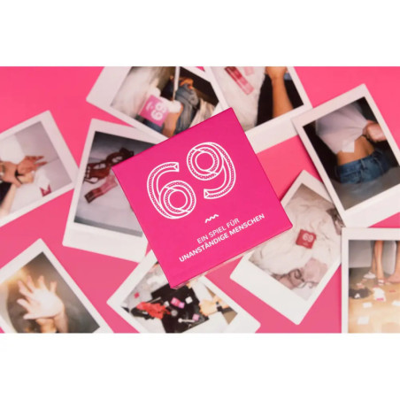Rosa Kartenspielbox mit der Aufschrift 69 liegt auf verstreuten Sofortbildern vor pinkem Hintergrund.