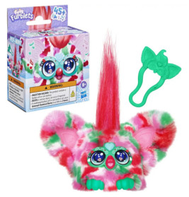 Bunter Furby mit großen Ohren, pinkem Haar und grünem Zubehör neben der Verpackung.