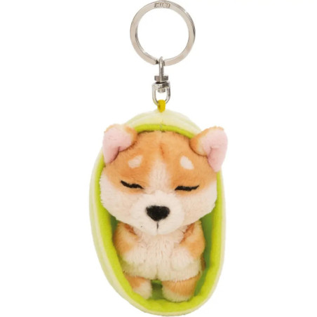Plüsch-Shiba-Inu-Schlüsselanhänger in grüner Erbsenschale, mit geschlossenen Augen, wirkt gemütlich.